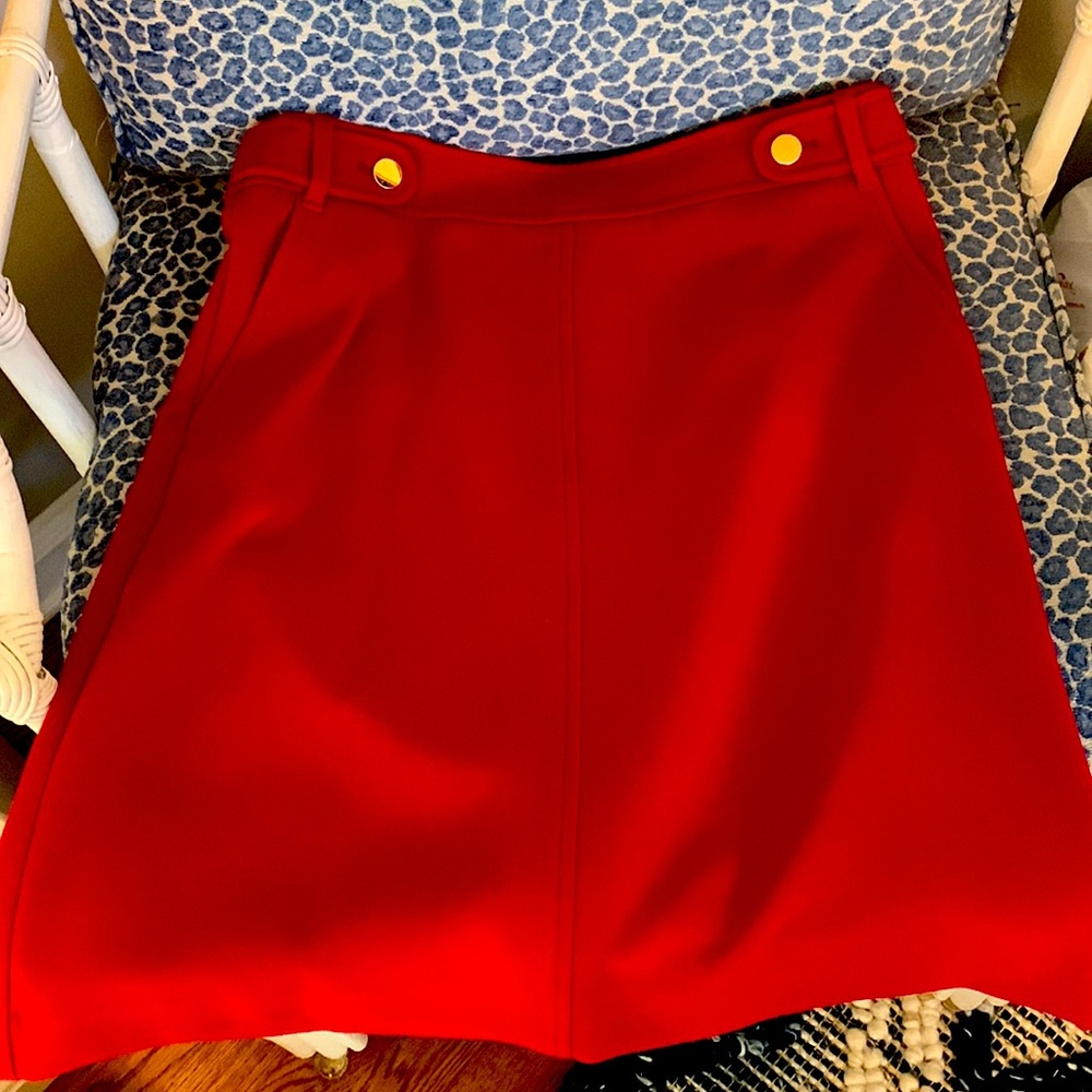 Red pencil skirt with gold buttons and exposed zipper at back